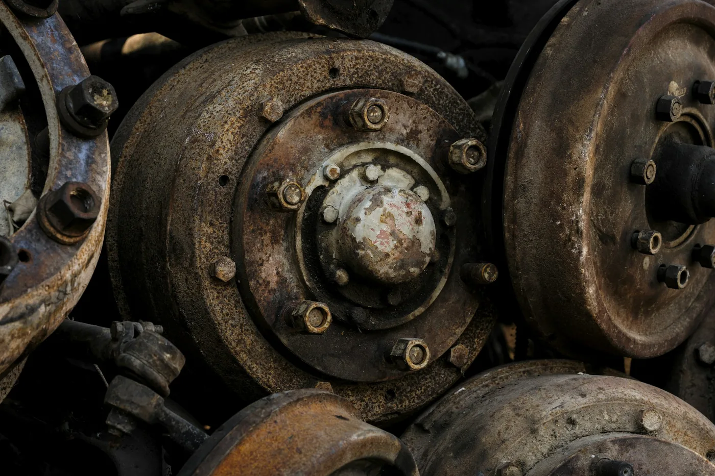 A stack of heavily corroded cast steel brake drums and hubs piled on top of one another